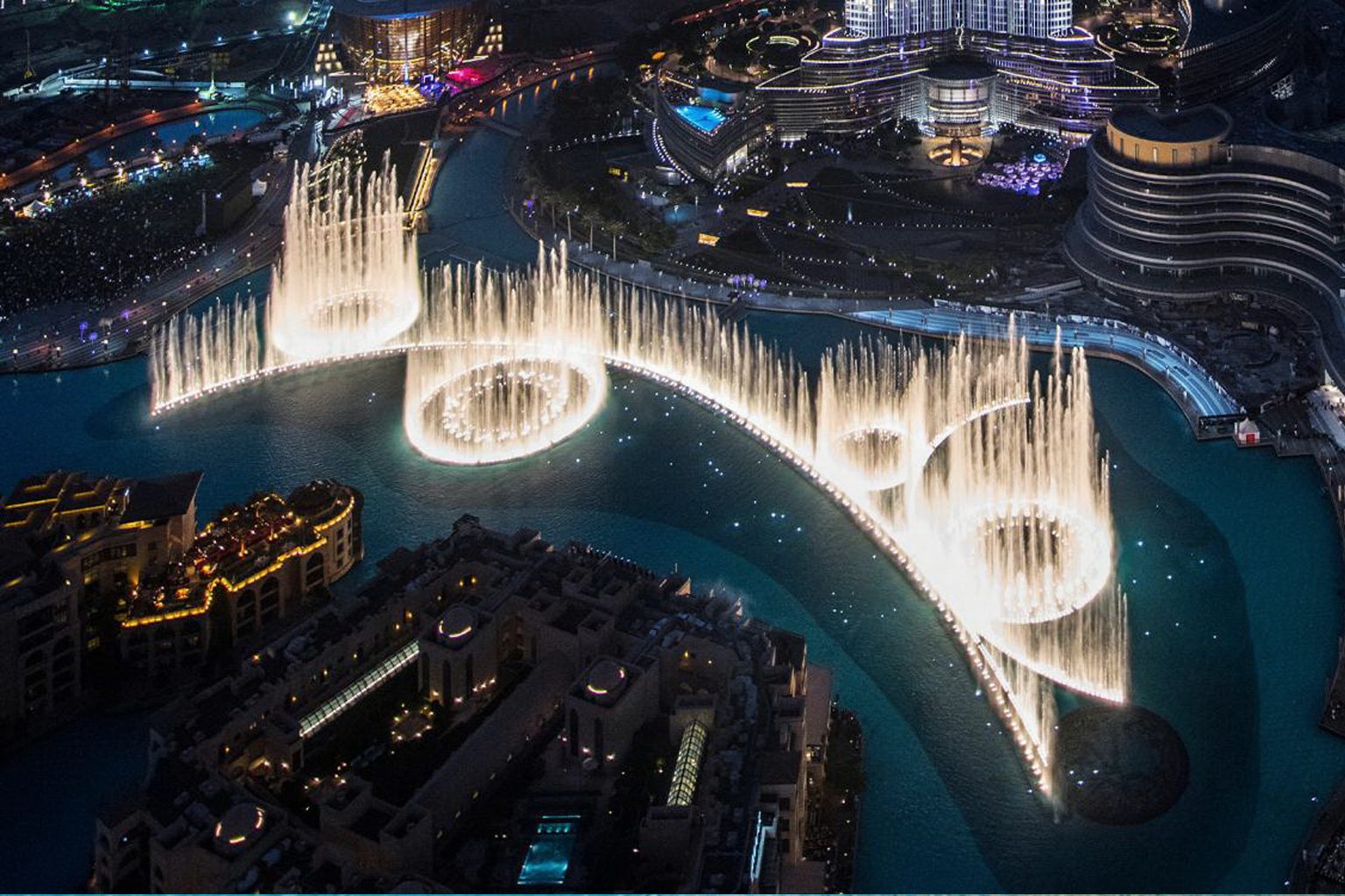 The Dubai Fountain in full spray on the lake, seen from above at night
